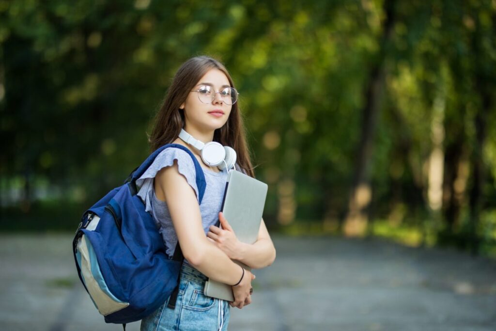 cheerful-attractive-young-woman-with-backpack-and-notebooks-standing-and-smiling-in-park-scaled-e1675190066118-1024x683 Vestibular UNIFACS 2025: Inscrições, Datas, Gabarito e Resultado