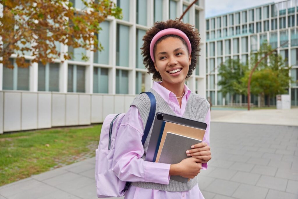 cheerful-schoolgirl-carries-rucksack-notepads-and-digital-tablet-looks-into-distance-with-happy-expression-walks-in-campus-during-daytime-female-student-returns-from-university-education-concept-scaled-e1674589718680-1024x684 Ciências Sociais 2025: Onde estudar, sobre o curso e Inscrição